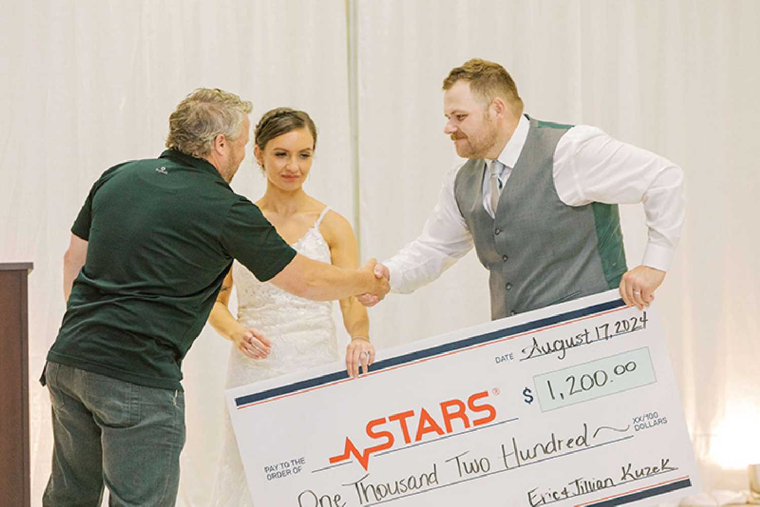 Bride Jillian Easton and groom Eric Kuzek presenting the cheque to Darren Entner with STARS.